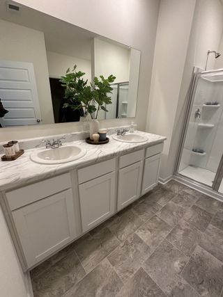 A modern bathroom with dual sinks, marble countertop, and a spacious glass-enclosed shower.
