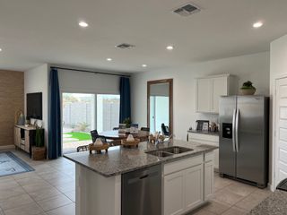 Modern kitchen with granite island, stainless steel appliances, and bright dining area opening to a landscaped patio.