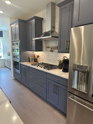 A sleek kitchen featuring modern slate blue cabinets, stainless steel appliances, and elegant lighting.