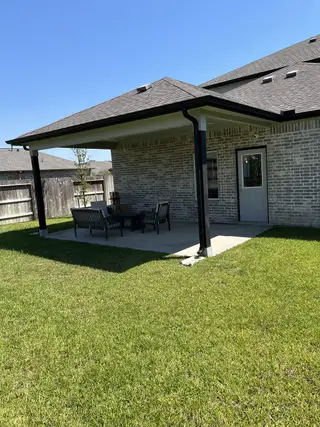 A charming covered patio in a lush backyard in Massey Oaks by CastleRock Communities (Pearland, TX).