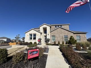 Street view A beautiful brick home with manicured landscaping in Stonewall Ranch 40s by Taylor Morrison (Liberty Hill, TX).