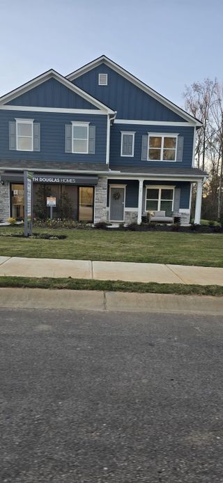 Charming blue two-story home with stone accents in Roxeywood Park by Smith Douglas Homes (Winder, GA).