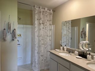 A cozy bathroom featuring a large mirror, double vanity, and a decorative fish theme with a patterned shower curtain.