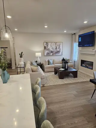 A cozy living space features a sectional sofa, abstract art, and a mounted TV. A kitchen island adds charm and function.