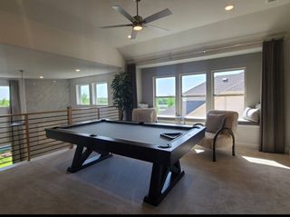 Model Home A chic game room with a sleek pool table, cozy seating by the windows, and modern ceiling fan.