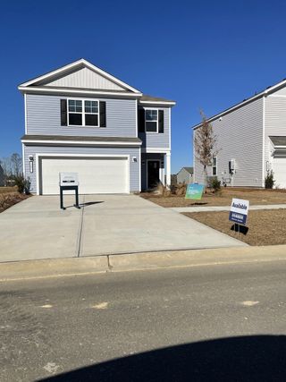 A charming gray two-story home with shutters and a spacious driveway in Carolina Groves by D.R. Horton (Moncks Corner, SC).
