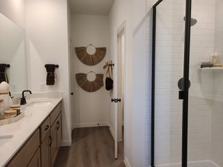 A modern bathroom with a sleek shower, spacious vanity, wood accents, and stylish decor.