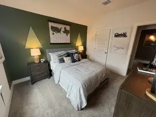Cozy bedroom with green accent wall, stylish decor, and comfortable furnishings.