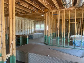 Model Home A house under construction featuring exposed wood framing and insulation. Ductwork visible in the ceiling.