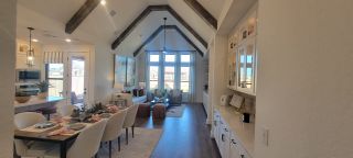 Model Home A spacious living area with vaulted ceilings, elegant dining setup, and abundant natural light, offering modern comfort and style.