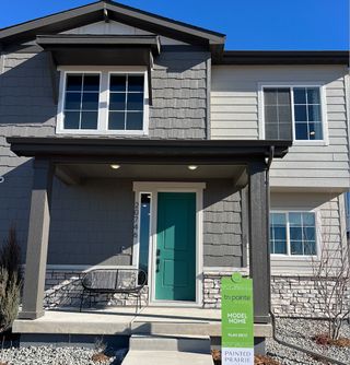 A sleek modern home with a teal door and stone accents in Painted Prairie by Tri Pointe Homes (Aurora, CO).