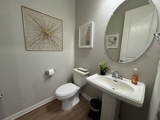 A stylish powder room with a pedestal sink, oval mirror, and elegant gold wall art.