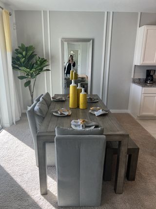 A stylish dining room with a rustic wood table, plush seating, and decorative yellow accents, creating a warm and inviting atmosphere.