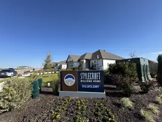 Street view A welcoming sign for Stylecraft Builders at Eastern Wells (Jarrell, TX) highlights the community's charm with a "Welcome Home" message and contact information.