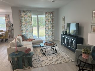 Model Home A cozy living room with a sectional sofa, floral curtains, and a stylish TV console for relaxed modern living.