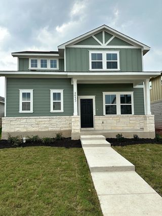 Street view A charming sage green home with a stone facade in The Hollows at Avery Centre by Century Communities (Round Rock, TX).