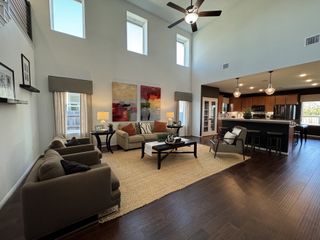 A spacious living area with high ceilings, modern furnishings, and an open kitchen with sleek lighting.