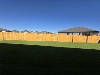A spacious backyard with a wooden fence in the 6 Creeks community by Pulte Homes, showcasing suburban tranquility (Kyle, TX).