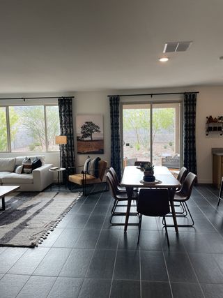 A modern living area with large windows, sleek tile flooring, and a cozy dining space, accented with contemporary decor.