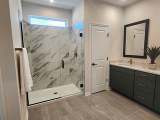 A modern bathroom featuring a spacious glass shower, sleek vanity with marble countertops, and elegant tile flooring.