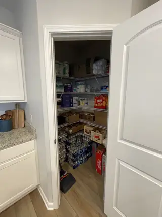 A well-organized pantry with ample shelving and storage for all essentials, featuring sleek white cabinetry and granite countertops.