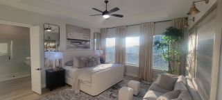 Model Home A bright bedroom with neutral tones, modern art, plush bedding, and elegant lighting, offering a cozy and serene retreat.