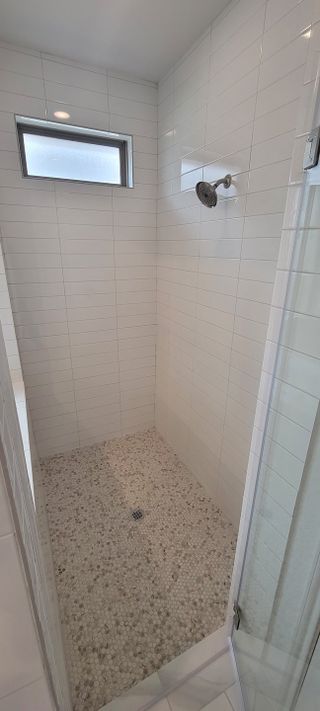 A stylish walk-in shower with white subway tiles, a pebble stone floor, and a sleek rainfall showerhead for a spa-like feel.