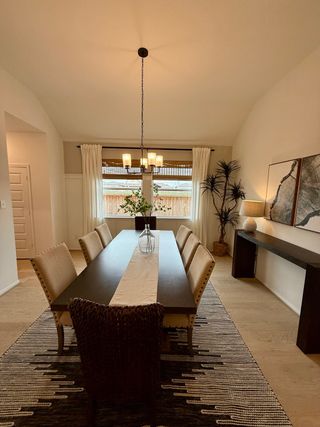 A formal dining room features a long dark wood table, upholstered chairs, and a statement rug, creating an elegant and inviting space.