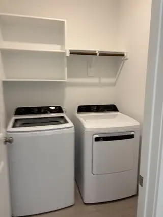 Model Home A functional laundry room with modern washer and dryer, open shelving, and clean design.