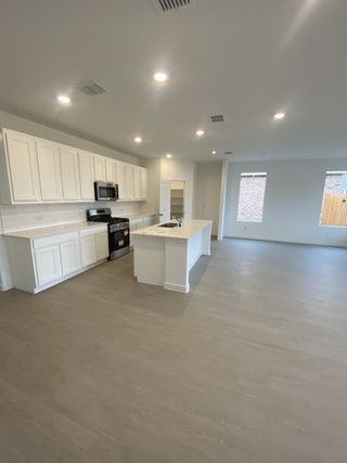 A spacious kitchen with white cabinetry, island, modern appliances, and recessed lighting.