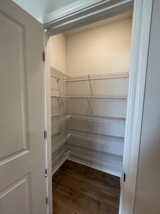 Model Home A spacious pantry with wire shelving and wood flooring, perfect for organized storage.