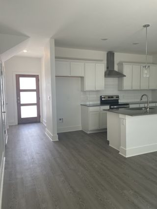 Model Home Bright, open kitchen with modern white cabinetry, grey flooring, and ample natural light.