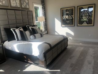 A luxurious bedroom with a plush headboard, stylish bedding, and vibrant geometric artwork.