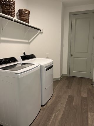 A sleek laundry room featuring modern appliances, wood-patterned flooring, and smart shelving with wicker baskets.