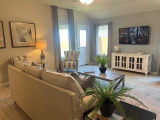 A cozy living room featuring a plush sofa, modern decor, and ample natural light streaming through large windows.