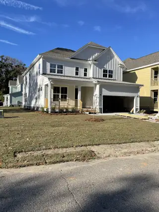 A charming white home with a welcoming porch in Overlook at Copahee Sound by Dream Finders Homes (Awendaw, SC).