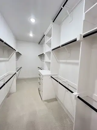 A spacious walk-in closet featuring ample shelving, hanging rods, and plush carpeting for a luxurious storage solution.
