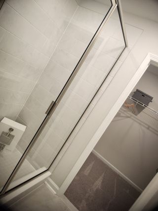 Model Home A modern bathroom features a sleek glass shower with white tiling and an adjacent walk-in closet.
