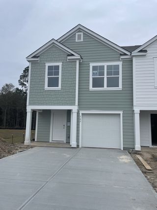 Street view A charming green townhouse with a white garage in The Townes at Merrimack by D.R. Horton (Moncks Corner, SC).