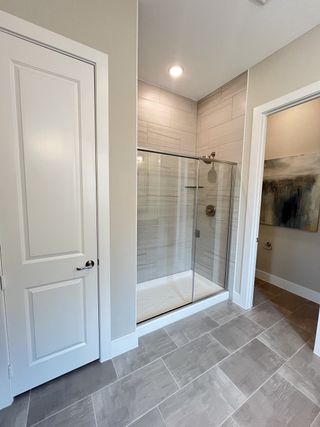 A sleek bathroom with a glass-enclosed shower, elegant tile flooring, and contemporary neutral walls.