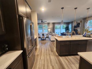 A modern open-concept kitchen with sleek cabinetry, stainless appliances, and an island overlooking a cozy living area.