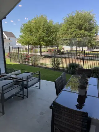 Model Home A tranquil patio with modern seating and views of a lush garden and trees, perfect for relaxation and outdoor dining.