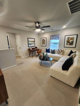 A cozy living room with a plush sectional, abstract art, and a ceiling fan, offering a modern and inviting space.