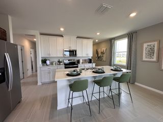 Model Home A modern kitchen with sleek white cabinets, stainless steel appliances, and a stylish island with green barstools.