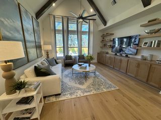 A stunning living room with vaulted ceilings, warm wood tones, and oversized windows showcasing a view of the backyard.