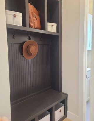 Model Home A chic mudroom with dark wood cubbies, hooks for storage, and a sleek bench. Perfect for organization and style.