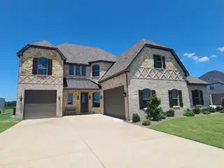 A beautiful stone and brick home with lush landscaping in Corner Stone Ranch by Astoria Homes (Howe, TX).
