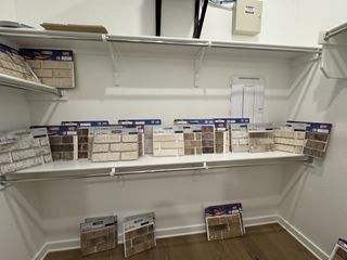 A display of various brick and stone tile samples arranged on white shelves in a showroom or design center