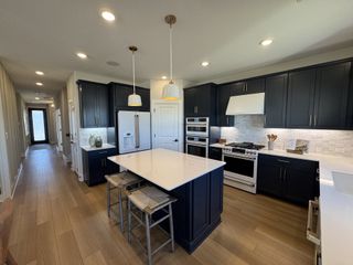 A sleek kitchen with dark cabinetry, a spacious island, and modern appliances.