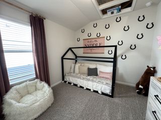 A cozy kids' room with a house-shaped bed, plush seating, horse decor, and soft carpet. Perfect for a playful, comfortable space.
